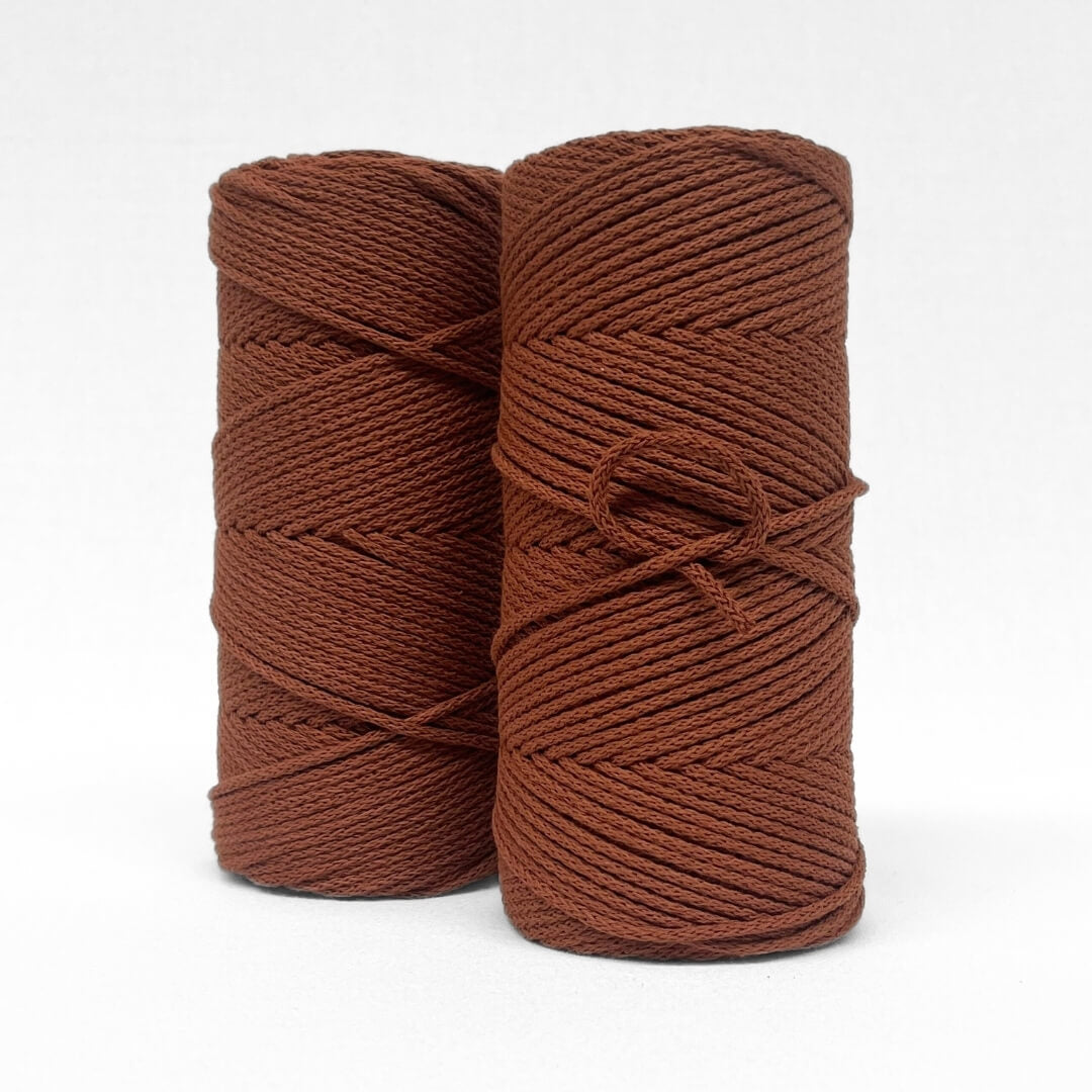 two rolls of burnt butter braided 4mm macrame cord on white background