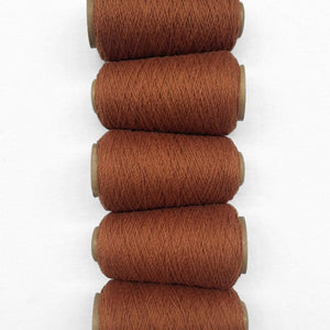 Brown sugar woolen yarn five rolls laying side by side vertically on white background showing up close texture
