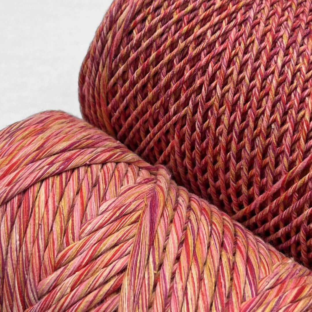 orange pink purple and yellow colour way of mixed string stnading side by side on white wall