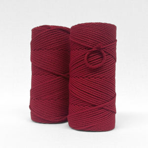 two rolls of 4mm braided cotton cord in chilli red standing side by side on white back drop