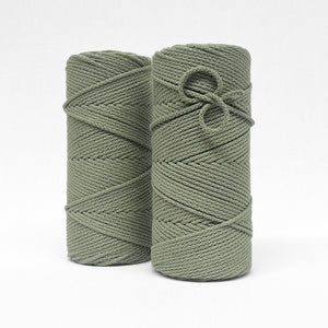 two rolls of sage green braided cotton macrame cord on white wall