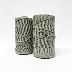 two rolls of sage green cotton string on white background for size comparison 