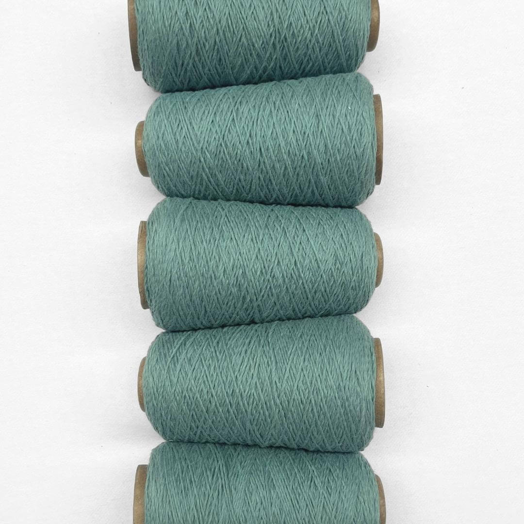 Five rolls of teal blue wool cord in flat lay image laying side by side on white background 