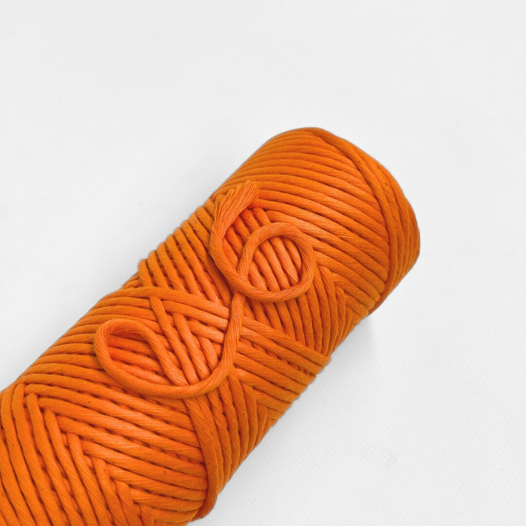 single roll of neon orange macrame cotton string on white background