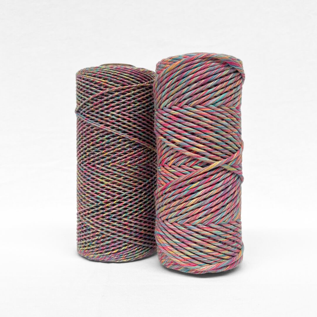image of two rolls showing size variation of harlequin mixed macrame string colour way is blue pink purple yellow blue green 1.5mm and 4mm variation on white background 
