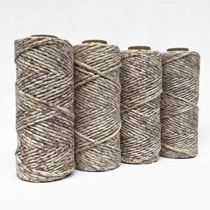 four rolls of purple and yellow mixed cotton string standing on angle with white background