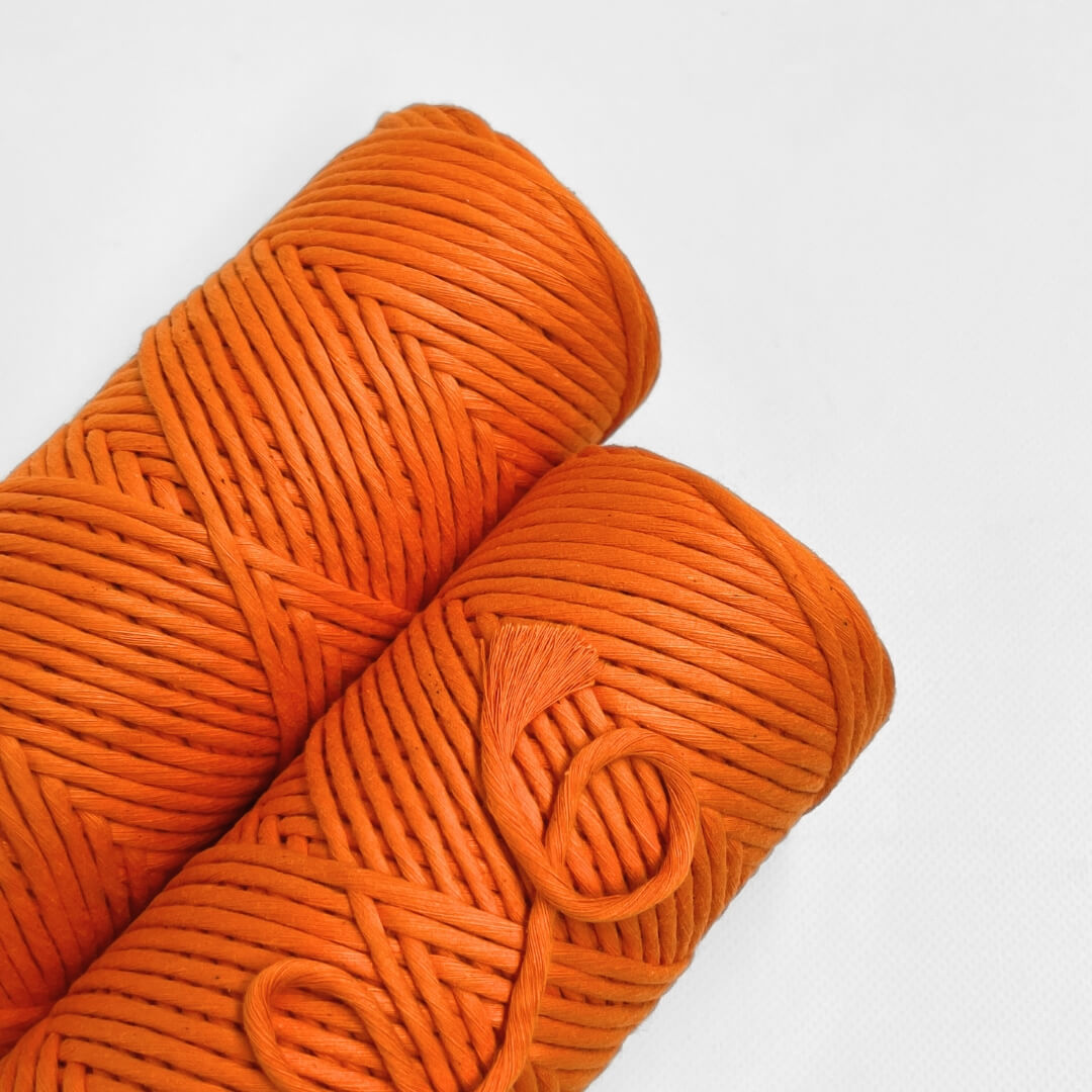 single roll of neon orange macrame cotton string on white background