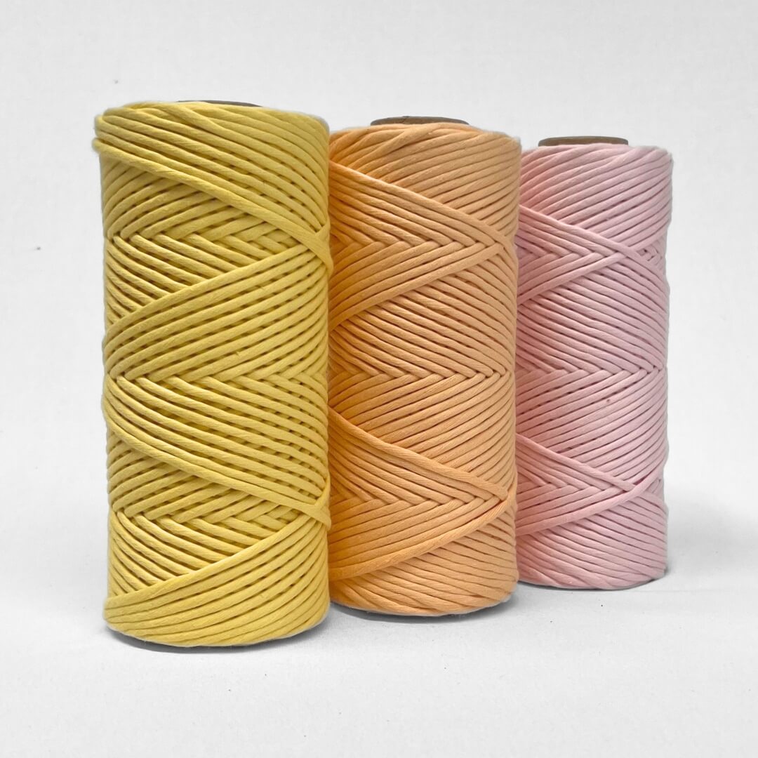 three rolls of 4mm cotton crd in buttercup apricot ice and frosted pink standing side ny side with white background