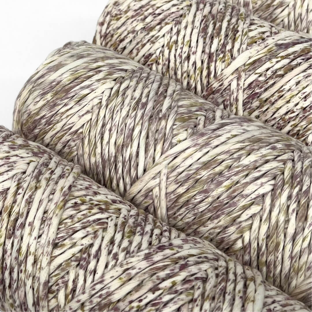 four rolls of purple and yellow mixed cotton string standing on angle with white background