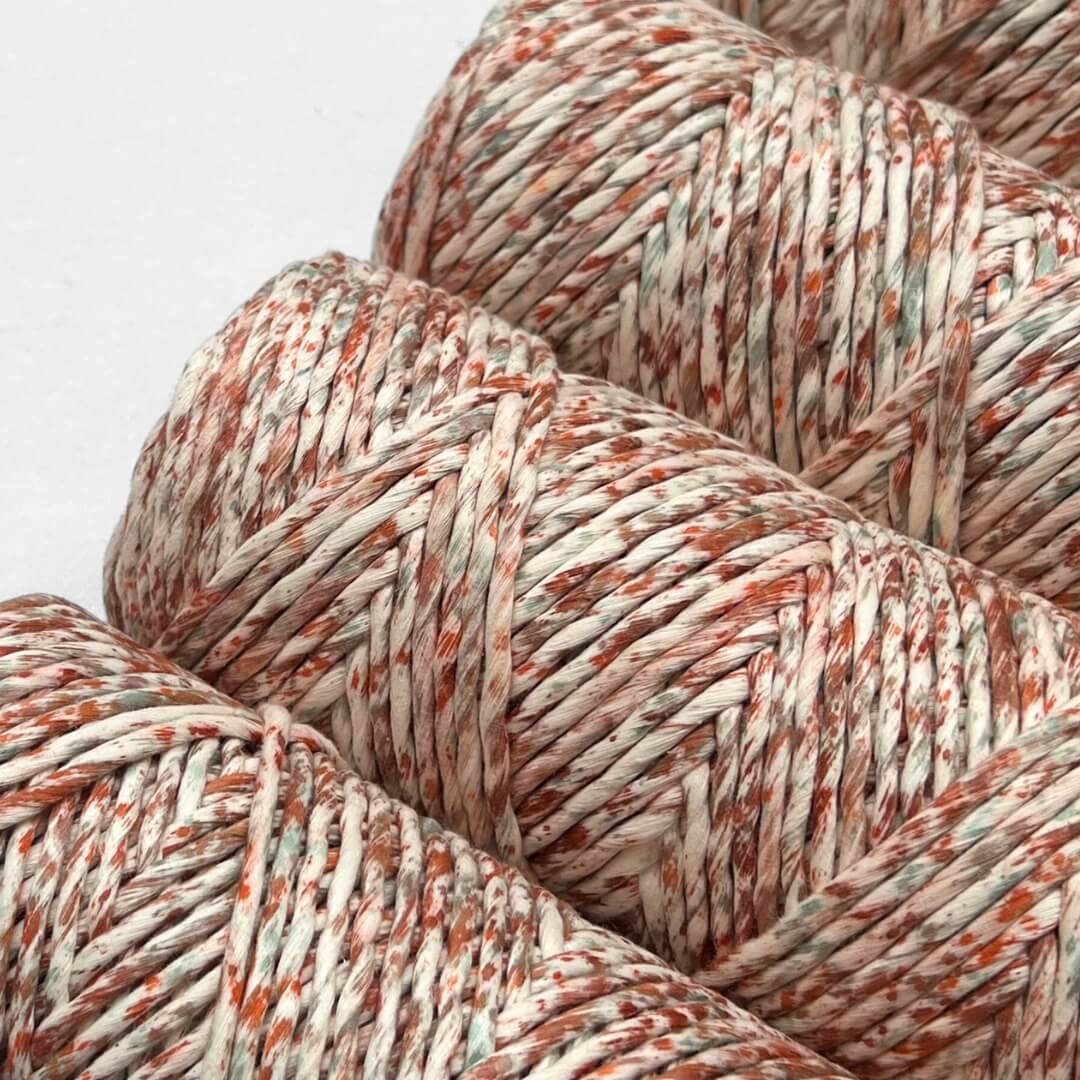 four rolls of confetti cotton string in red and green colourwau standing side by side on angle on white background