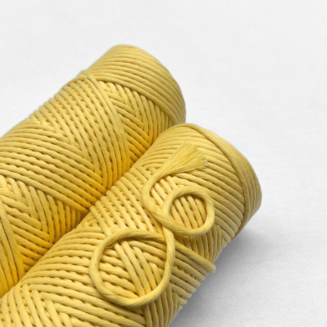 two rolls of buttercup yellow macrame string laying flat on white background