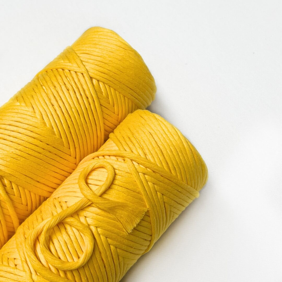 two rolls of daffodil yellow cotton macrame and weaving cord laying flat on white background