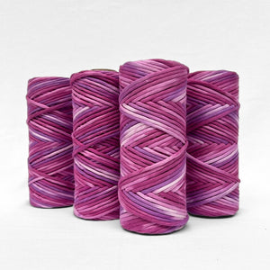 four rolls of very berry bold purple hand painted cotton cord standing side by side on white wall