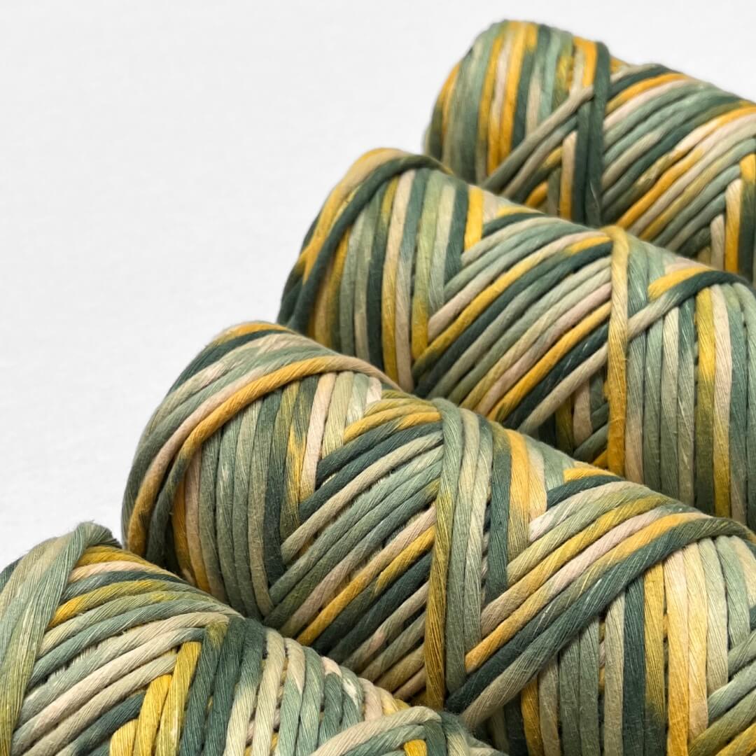 four rolls of wattle yellow and green hand painted string standing on white background