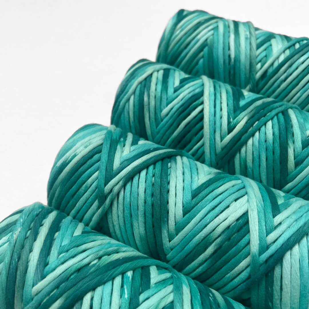 flour rolls of hand painted string in colour blue lagoon which consist of deep green and bright blue standing side by side angled on white back drop