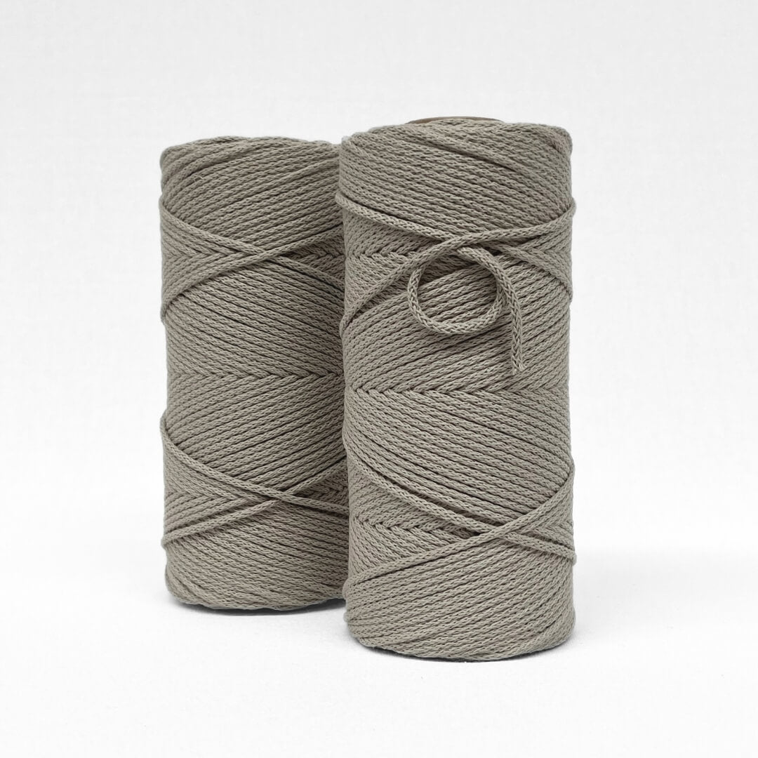 two rolls of latte brown braided cotton cord standing side by side on slight angle with with background