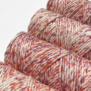 close up image showing four rolls of orange and purple speckled string laying flat