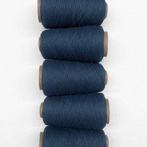 Navy Blue woollen yarn in flat lay showing five rolls of same colour laying side by side vertically down screen on white background showing up close texture 
