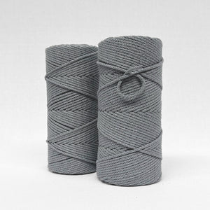 two rolls of stromg grey braided cotton macrame cord standing side by side on white background