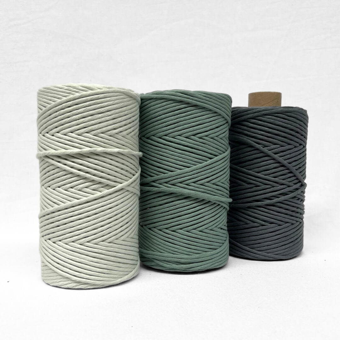 two rolls of medium green cotton macrame string on white background showing softness and texture