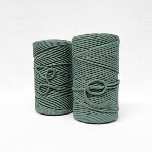 two rolls of medium green cotton macrame string on white background showing softness and texture
