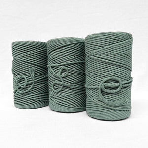 three rolls of cotton in medium green on white wall showing size and textural differences