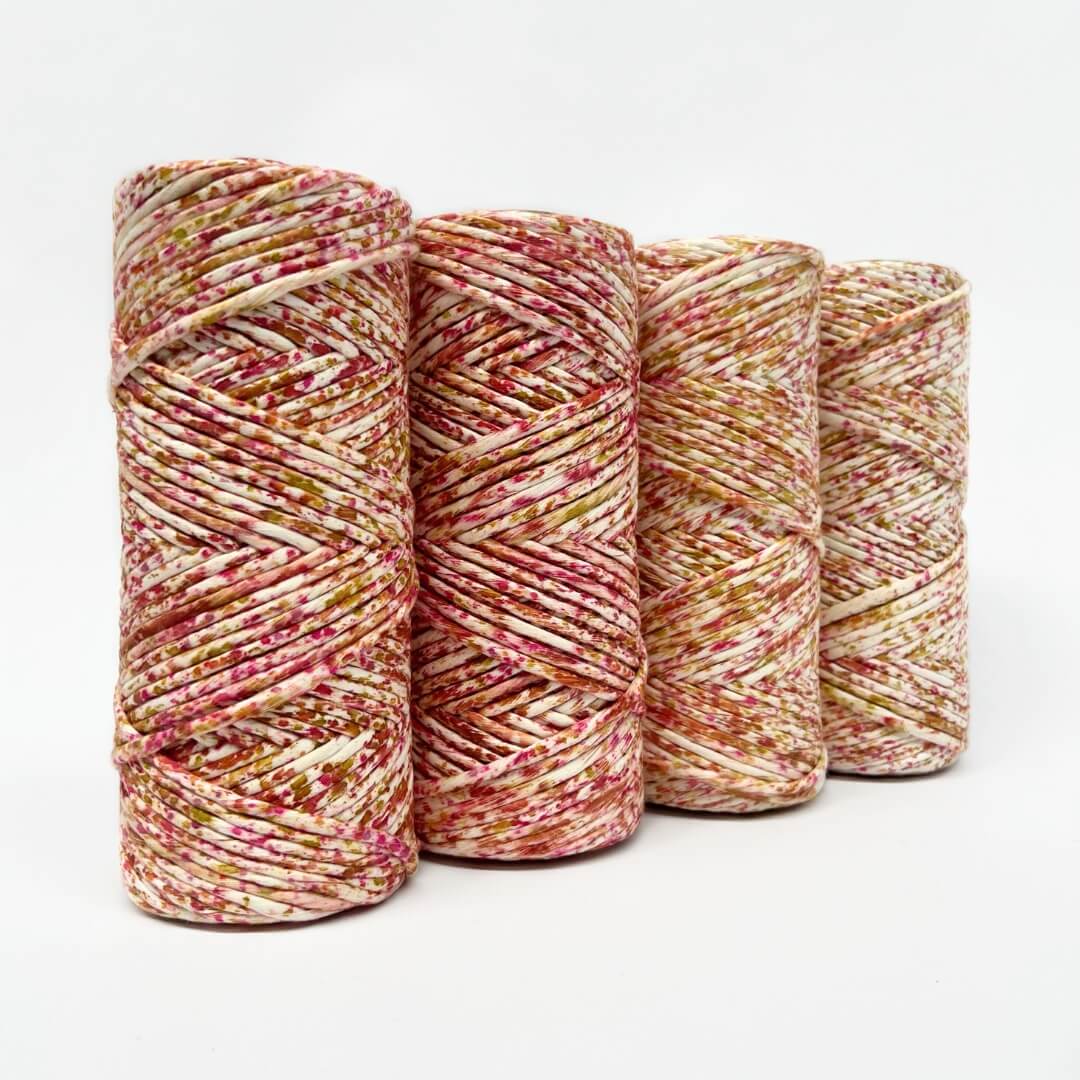 four rolls of pink, orange and yellow confetti macrame cord on white background