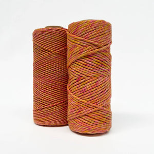 two rolls of yellow, pink & orange mixed macrame string standing side by side on white wall showing 4mm and 1.5mm variants