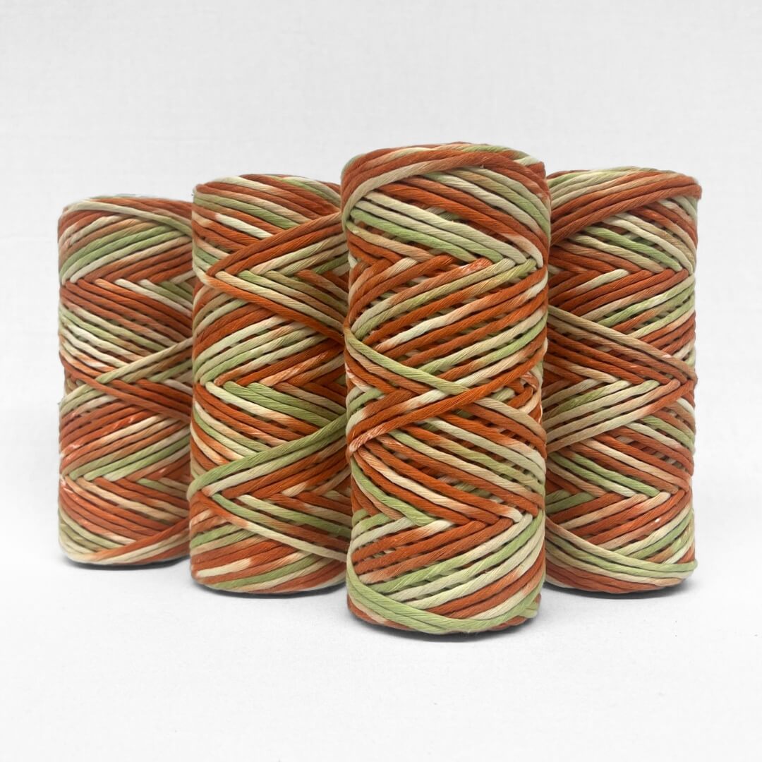 four rolls of Banksia red and green hand painted string standing on white back ground