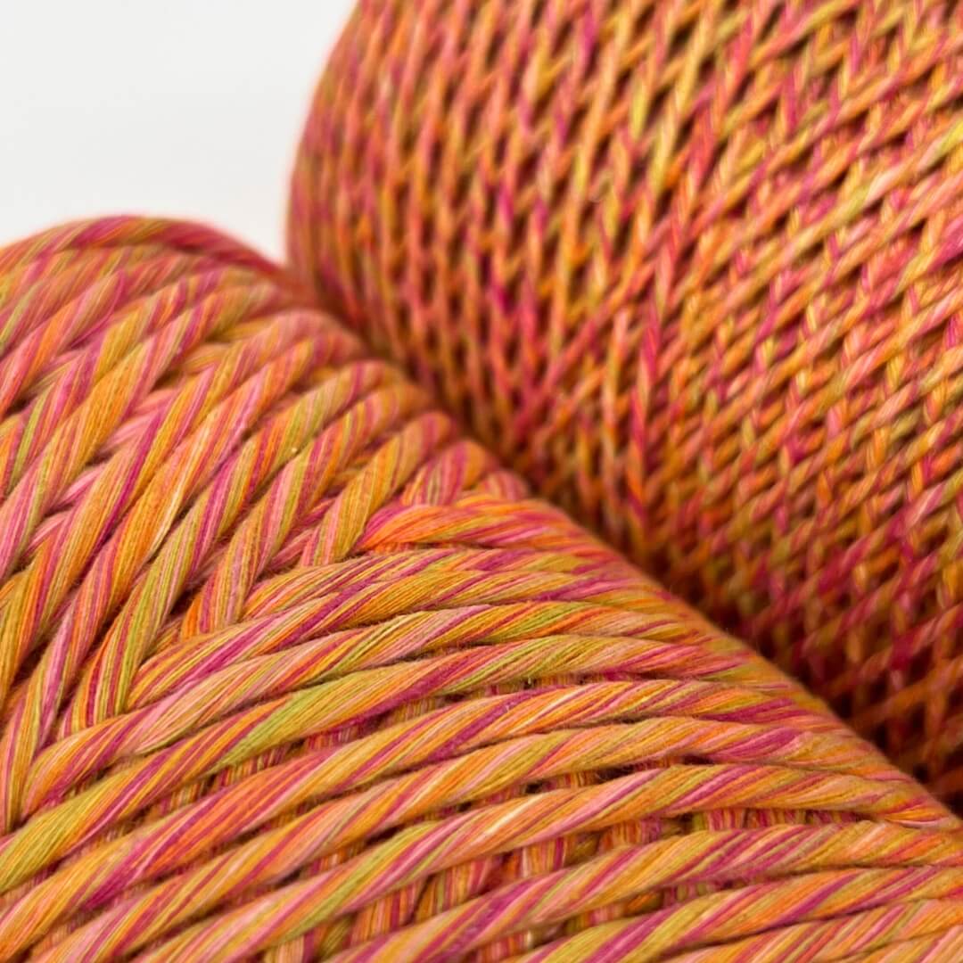 two rolls of yellow, pink & orange mixed macrame string standing side by side on white wall showing 4mm and 1.5mm variants