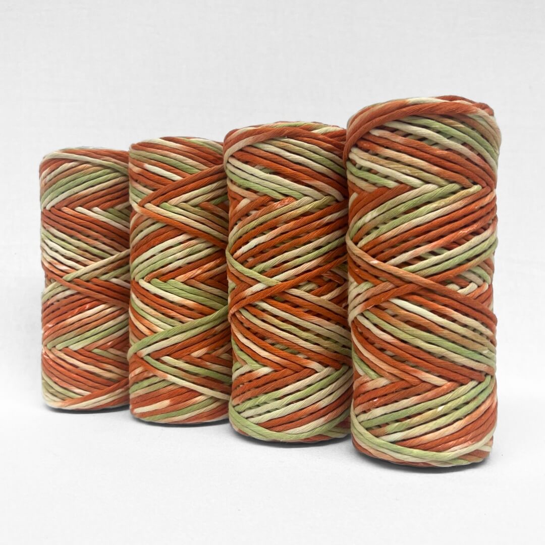 Banksia red and green hand painted string image showing four rolls standing up right on angle on white background