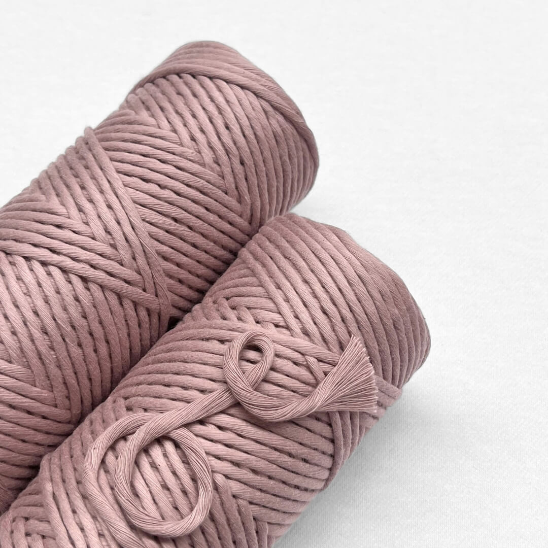 wo rolls of dusty purple coloured macrmae cord laying flat and side by side on white background