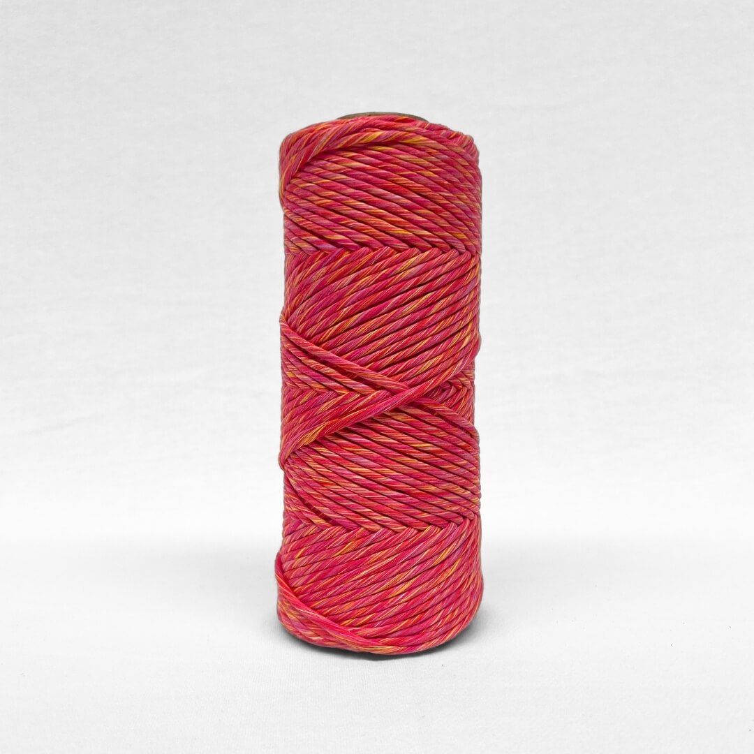 image of one roll of 4mm sunburst cotton macrame mixed cord vibrant pink yellow and red colour way standing up against white wall