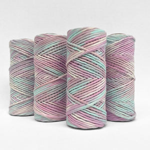four rolls of unicorn hand painted string standing upright on white background 