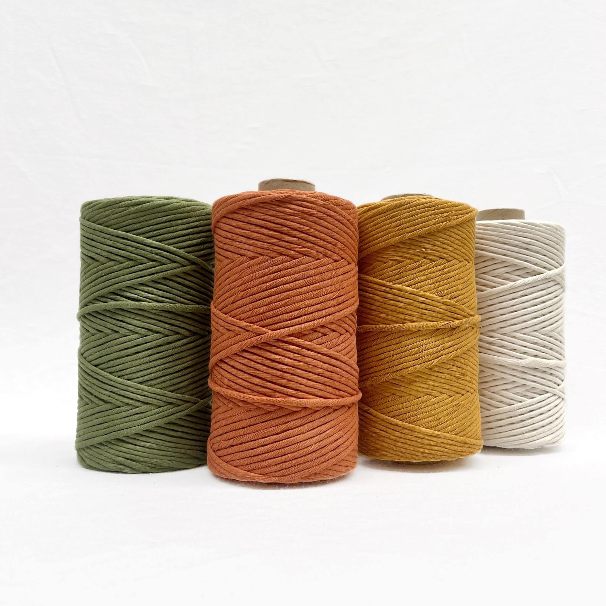 olive green burnt orange mustard yellow natural group photo of four cotton strings on white wall