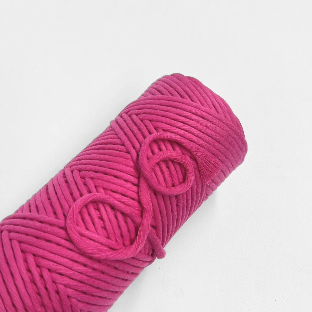 single roll of hot pink macrame cord on white background 