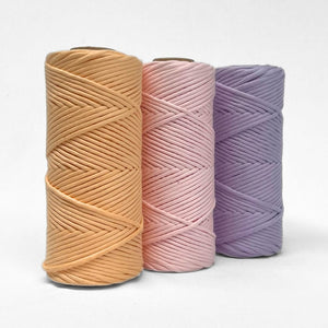 three rolls of macrame cord in apricot ice marshmallow pink and pastel purple standing side by side on white background showing complimenting colour palette 