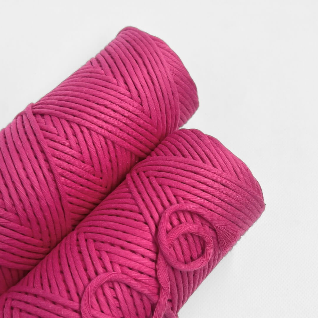 single roll of hot pink macrame cord on white background 