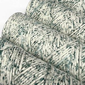 close up image of green oasis confetti cotton string for unique macramé and weaving projects on white backdrop