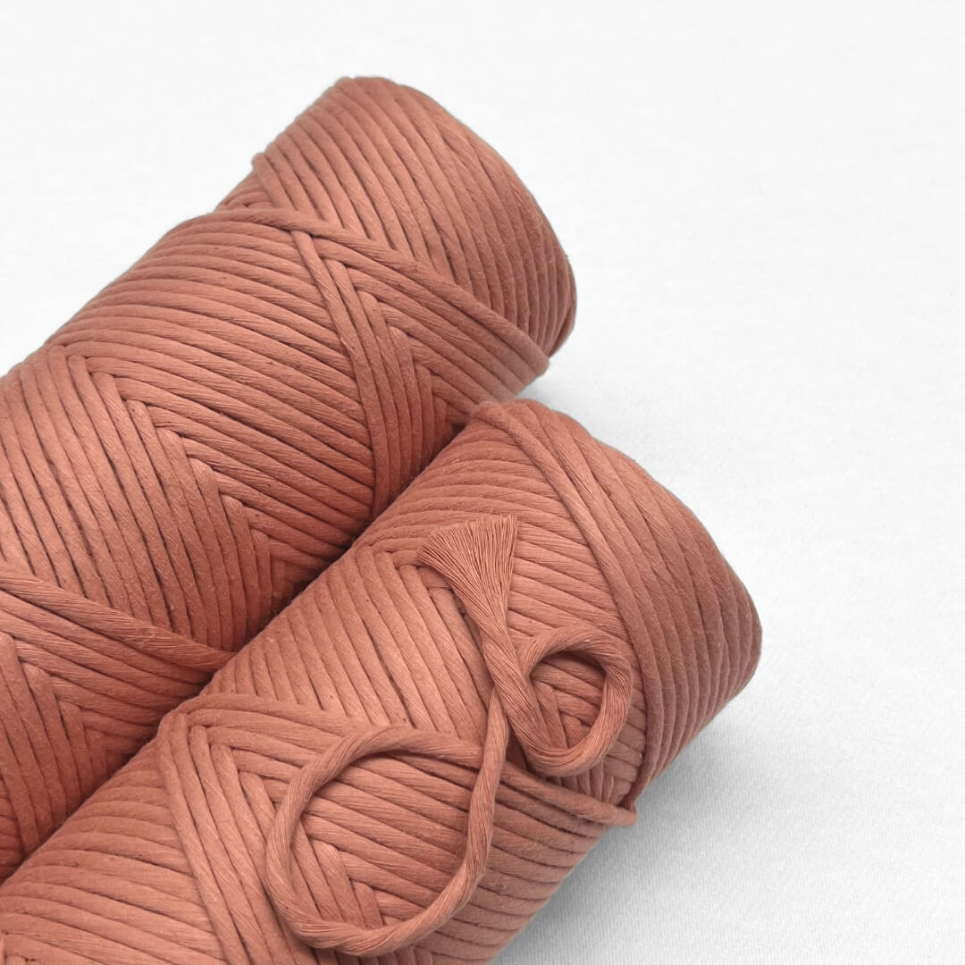 two rolls of rose wood macrame cord laying side by side on white background