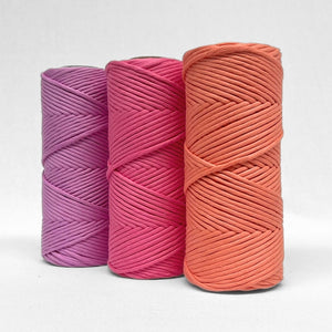 image showing three rolls of vibrant cotton in vivid violet, pink power and coral crush standing side by side on white background