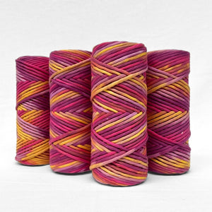 four rolls of electric sunset bold hand painted string luxury macrame cord standing upright in white background 