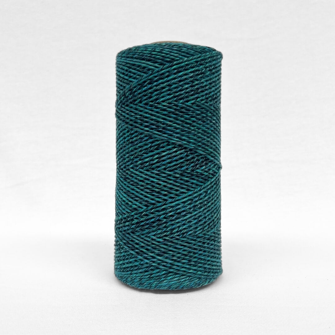 single roll of vibrant blue and black mixed cotton cord in 1.5mm standing alone on white back drop 