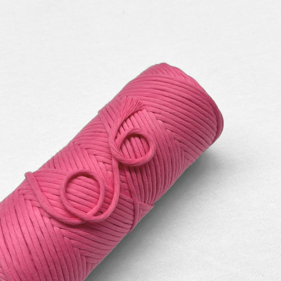 Single rolls of power pink pemium cotton cord laying flat on white background 