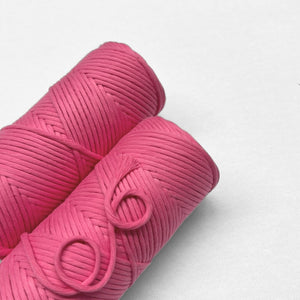 two rolls of cotton cord in pink colourway laying flat with white back drop to emphasise bright colour