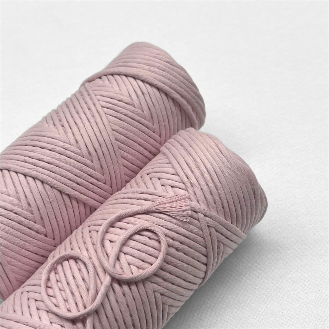 two rolls of macrame cord in muted pink colourway laying flat on white background 
