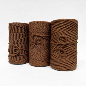 three rolls of chocolate brown cotton cord including 3mm string 5mm string and 4mm rope in white background 