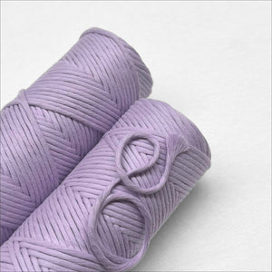 two rolls of pastel purple macrame cotton cord laying flat side by side on white background 