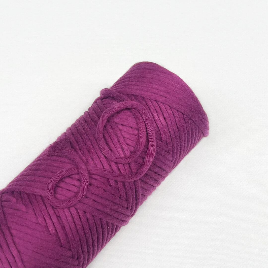 single rolls of cloud 9 luxe macrame cord in colur rich orchid vibrant purple laying flat on white background