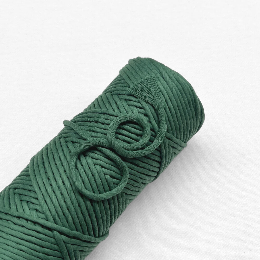 evergreen macrame cord laying flat on white background with smaller brushed out piece highlighting product softness